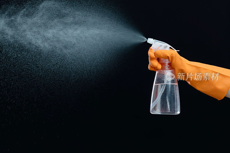 Hand using spray bottle on black background